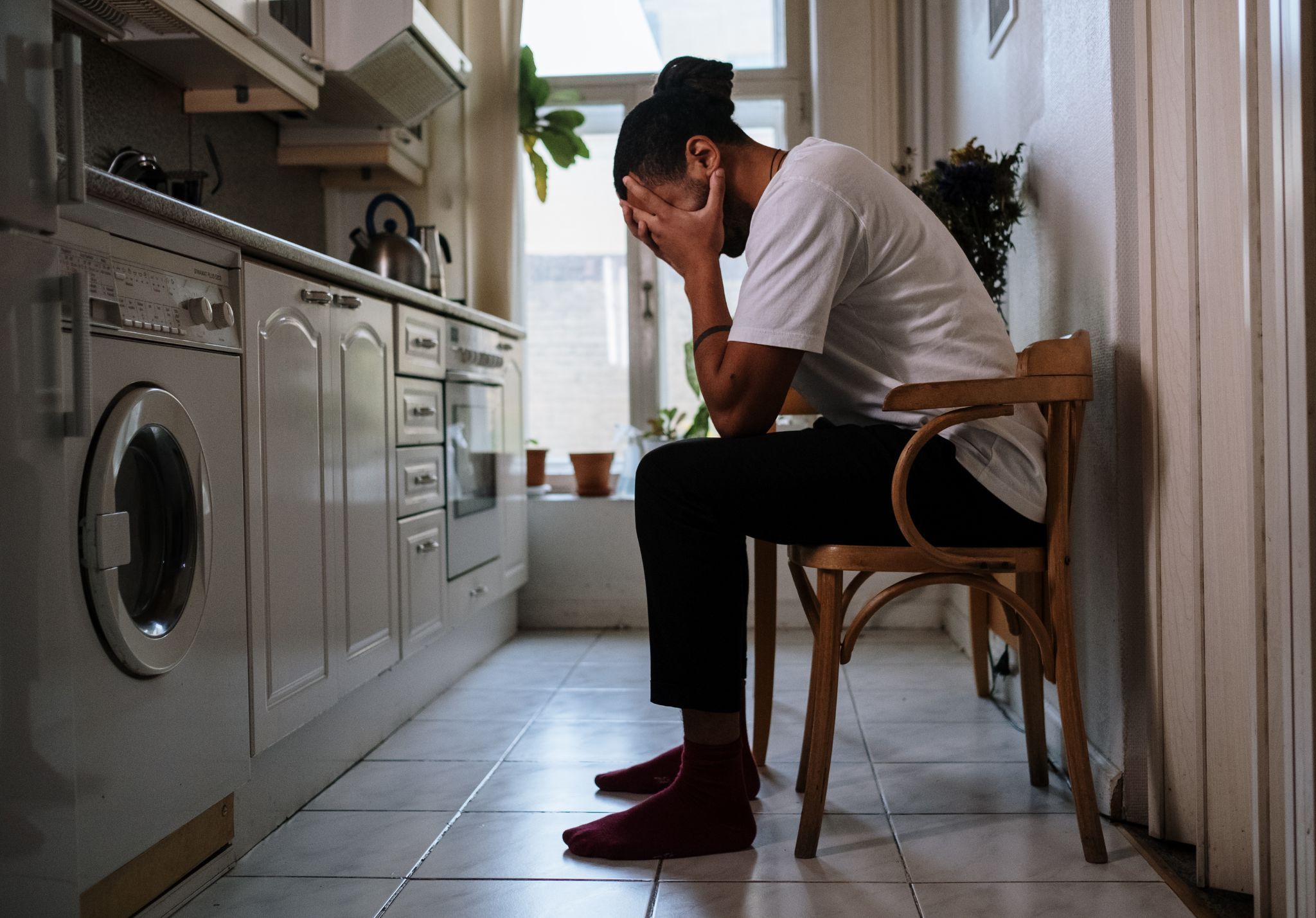Hombre sentado en la cocina con la cabeza entre las manos por ansiedad