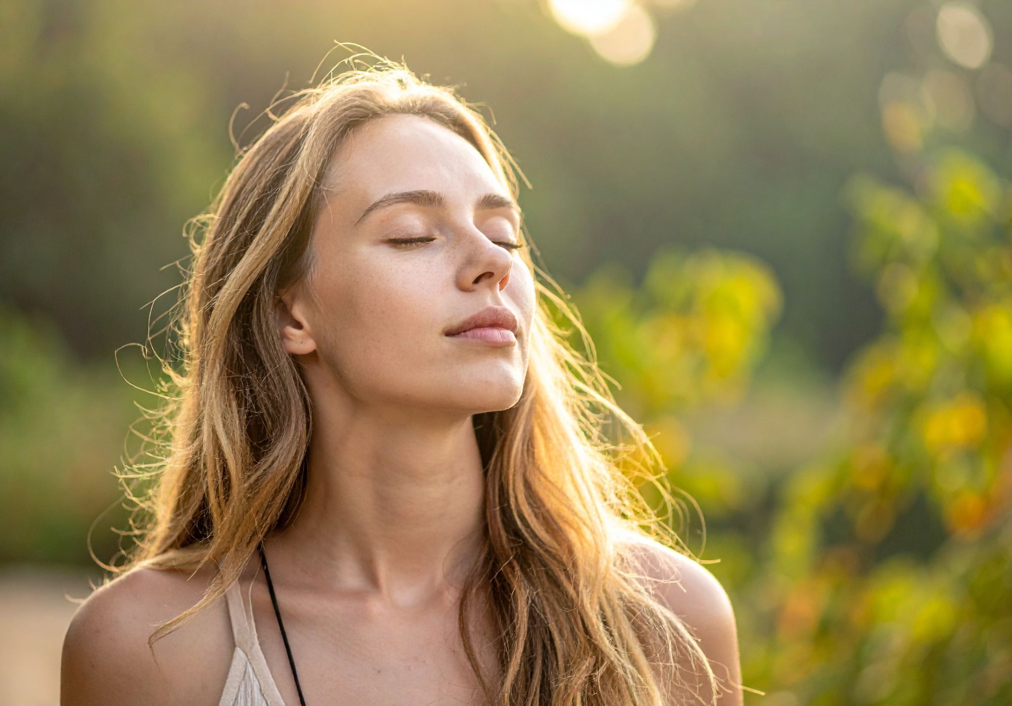 Mujer con los ojos cerrados respirando con calma al aire libre
