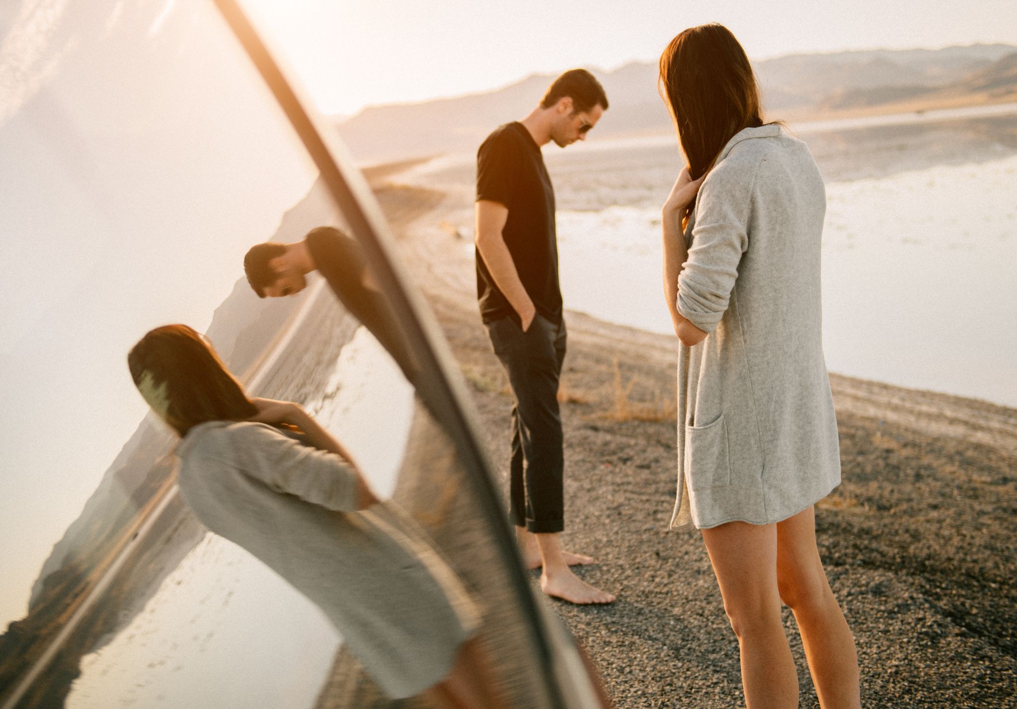 Pareja separándose en la orilla, reflejo del duelo amoroso