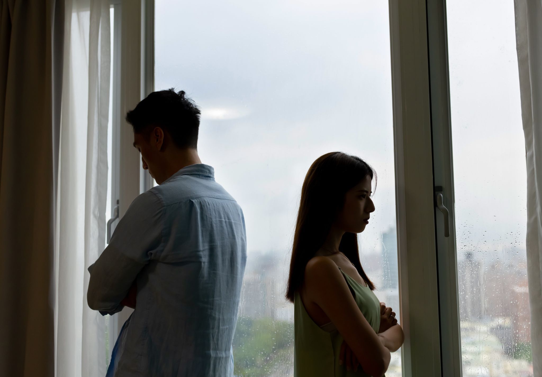 Pareja distanciada mirando por la ventana